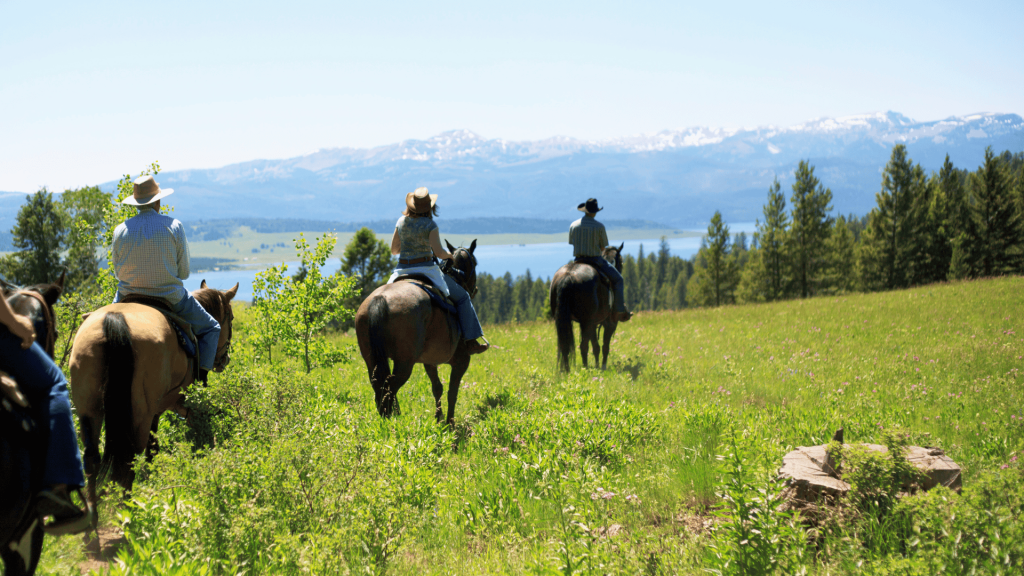 Horseback riding through open meadows with Rocky Mountain lake views near Entrance, Alberta