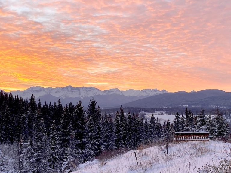 dawn sky over a snowy landscape with the rocky mountains in the background